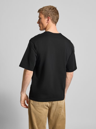 Männermodel trägt T-Shirt mit Label-Print von Levi's®, schwarze Baumwolle, lockerer Schnitt, Rückenlänge 70 cm, Ganzkörperansicht Rückansicht.