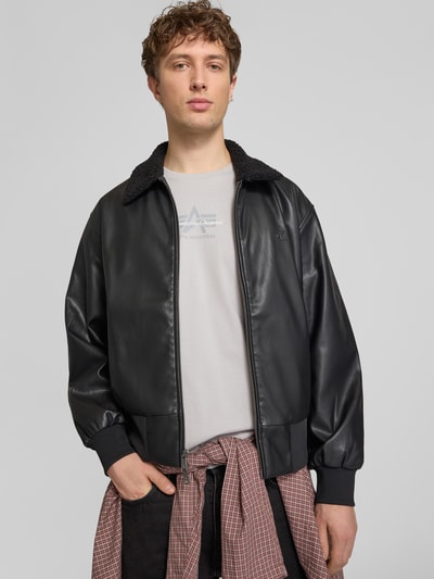 Męski model nosi T-Shirt mit Label-Detail od Alpha Industries z bawełny, prosty krój, okrągły dekolt, długość tyłu 68 cm, Ganzkörperansicht von vorne.