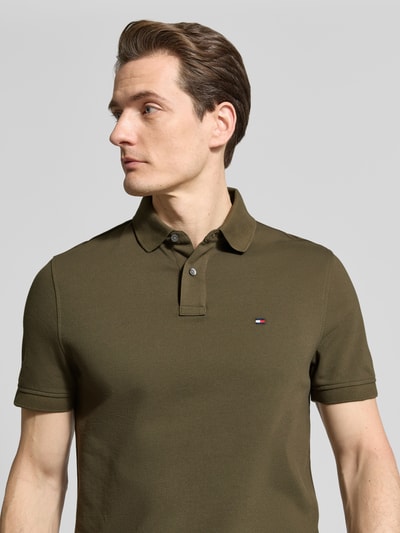 Männermodel trägt Regular Fit Poloshirt aus Baumwoll-Mix von Tommy Hilfiger, Optik: Unifarben, Logo-Stitching, Nahaufnahme Oberkörper.