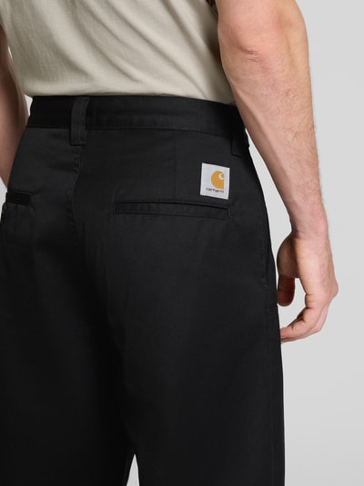 Männermodel trägt Chino mit Gesäßtaschen Modell 'BRADY' von Carhartt Work In Progress in Schwarz, lockerer Schnitt, Detailaufnahme Rücken.
