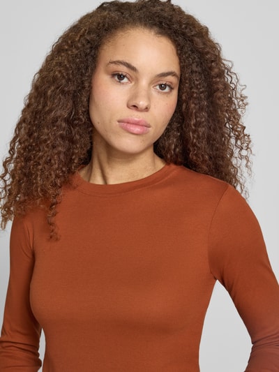 Kobiecy model nosi bluzkę z długim rękawem z okrągłym dekoltem EVERYDAY od Topshop, bawełna, krój regular fit, długość tyłu w rozmiarze S 53 cm, kolor rdzawy, prosta faktura, zbliżenie na górną część ciała