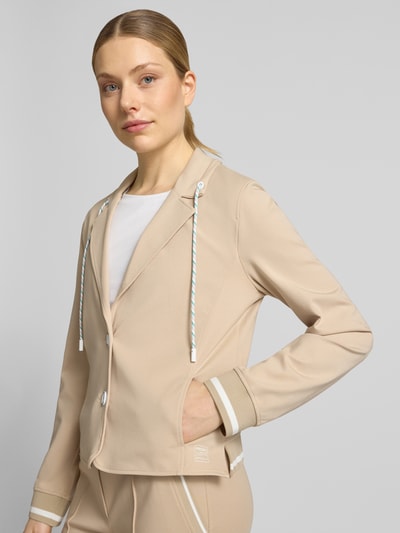 Vrouwenmodel draagt Regular Fit Blazer mit Eingrifftaschen van Marc Cain in beige, mix van katoen en modal met stretch, steekzakken, knoopsluiting, reverskraag met tunnelkoord, elastische mouwboorden, ruglengte maat 36: 55 cm, borstwijdte: 49 cm, mouwlengte: 63 cm. Nahaufnahme bovenlichaam vooraanzicht.