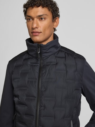 Męski model nosi Kurtka pikowana Regular Fit Steppjacke mit Stehkragen Modell 'AVIO FLEX 2.0' od Strellson, efekt: jednolity kolor, funkcja: wiatroodporna, kieszenie zapinane na zamek błyskawiczny, zamek błyskawiczny kryty, długi rękaw, prążkowane zakończenie rękawów, model z tunelową stójką, widok: z przodu, zbliżenie na górną część sylwetki.