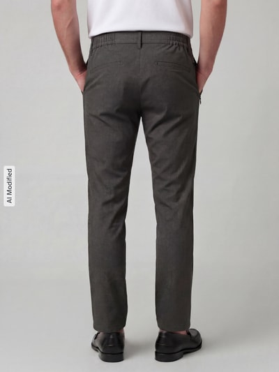 Männermodel trägt Tapered Fit Stoffhose mit Viskose-Anteil Modell 'Phil' von Brax in Dunkelgrau, Herren Gerade Hose, Ganzkörperansicht Rückansicht.