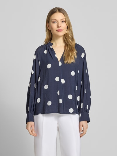 Frauenmodel trägt Bluse aus Viskose-Mix mit Serafino-Ausschnitt von Christian Berg Woman, dunkelblau mit weißen Punkten, Loose-Fit, Damen Bluse, verlängerter Rücken, Rückenlänge 61 cm, Ärmellänge 60 cm, Ganzkörperansicht von vorne.