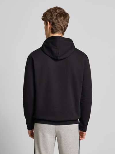 Männermodel trägt Hoodie mit Kapuze von adidas Originals in Schwarz, lockerer Schnitt, Baumwoll-Mix, Ganzkörperansicht Rückansicht