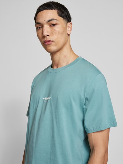 Männermodel trägt T-Shirt mit Logo und Rundhalsausschnitt von Jack & Jones in Hellblau, aus Bio-Baumwolle, Regular Fit, Nahaufnahme Oberkörper.