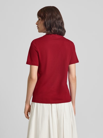 Vrouwenmodel draagt Regular Fit t-shirt van puur katoen model 'PAULINA' van VERO MODA in effen rood, Ganzkörperansicht Rückansicht.