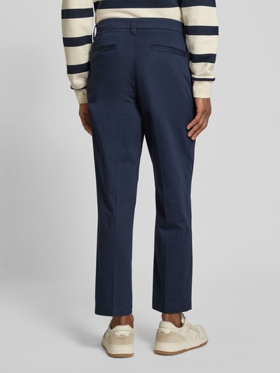 Männermodel trägt Regular Fit Chino aus Baumwoll-Mix Modell 'TAAMIR PLEATED' von Armedangels, unifarben, Ganzkörperansicht Rückansicht.