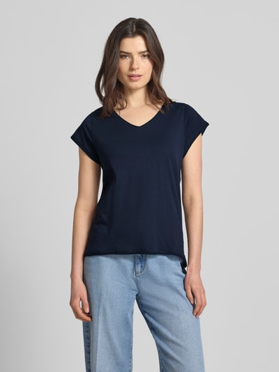 Kobieta nosi damski t-shirt z dekoltem w serek marki Christian Berg Woman z bawełny, krój regular fit, zrolowany brzeg, długość tyłu 59 cm, widok na całe ciało z przodu.