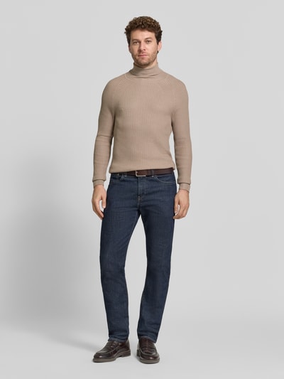 Mannenmodel draagt Rollkragenpullover aus Viskose-Mix in Ripp-Optik van Antony Morato, slim fit, beige, gecombineerd met een blauwe jeans, volledige vooraanzicht.