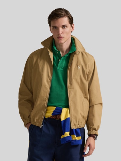 Mannenmodel draagt Regular Fit blouson uit puur katoen van Polo Ralph Lauren, look: effen, ritssluiting, logodetail, platte kraag, lange mouw, elastische rompzoom en mouwboord, zijsteekzakken, regular fit pasvorm, kleur beige, pure katoen; frontale opname van het bovenlichaam.