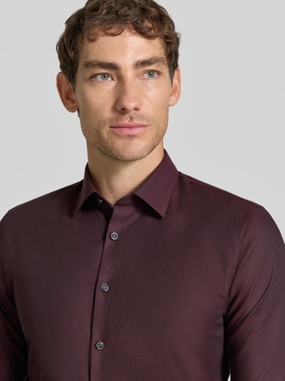 Männermodel trägt Super Slim Fit Businesshemd aus Baumwoll-Mix von OLYMP No. Six, weinrot, feine Struktur, Nahaufnahme Oberkörper.
