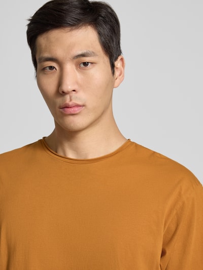 Männermodel trägt T-Shirt mit Rundhalsausschnitt und Label-Detail von Scotch & Soda, reine Baumwolle, Regular-Fit, Nahaufnahme Oberkörper.