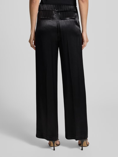 Vrouwenmodel draagt Opus stoffen broek van zuivere viscose, los model, elastische band, steekzakken, model 'Mucia', achteraanzicht.