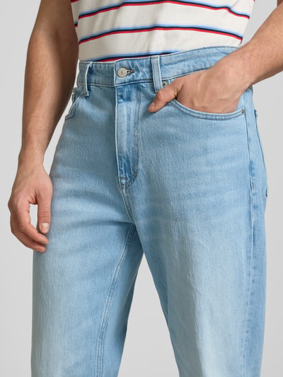 Männermodel trägt Tapered Fit Jeans aus Baumwoll-Mix Modell 'SONNY' von Tommy Jeans in hellem Denim, 5-Pocket-Design, Nahaufnahme Oberkörper.