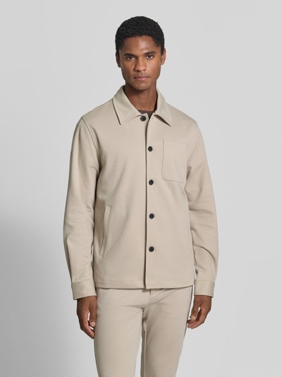 Männermodel trägt Slim Fit Hemdjacke mit Viskose-Anteil von Lindbergh in Beige, sichtbare Knopfleiste, Brusttasche, Ganzkörperansicht von vorne. Elastischer Material-Mix, glatte Textur, Umlegekragen, Eingrifftaschen, Rückenlänge bei Größe M: 70 cm.