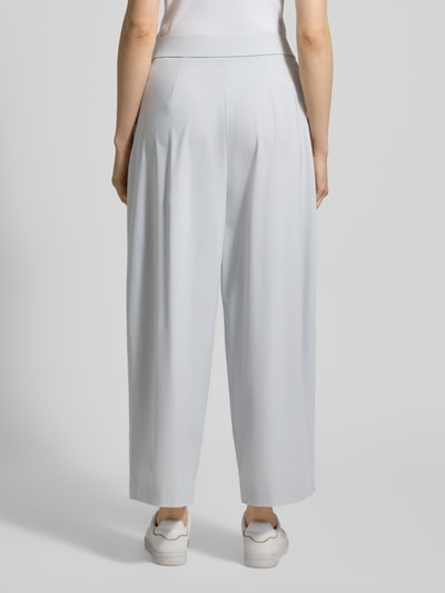 Frauenmodel trägt Hose mit gelegten Falten Modell 'MAYLA 6/8 JOGG' von Raffaello Rossi, hellgrau, elastischer Bund, weites Bein, Ganzkörperansicht Rückansicht.