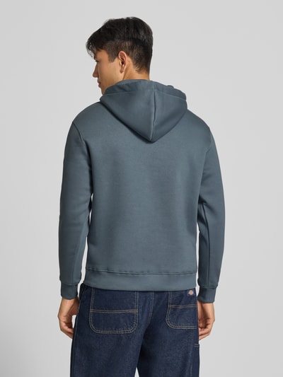 Männermodel trägt Regular Fit Hoodie aus Baumwoll-Mix mit Logo-Print von Alpha Industries in Blau, Rückenansicht, Kontext Herren Hoodie.