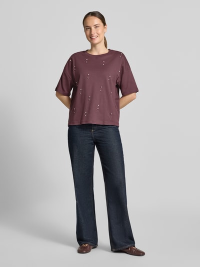 Frauenmodel trägt T-Shirt aus reiner Baumwolle von Christian Berg Woman in Bordeaux mit Ziersteinen, lockere Passform, Ganzkörperansicht von vorne.