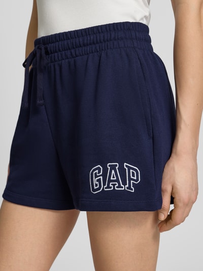 Frauenmodel trägt Sweatshorts mit Logo und elastischem Bund von GAP aus dunkelblauem Baumwoll-Mix, Regular-Fit, Nahaufnahme Oberschenkel.