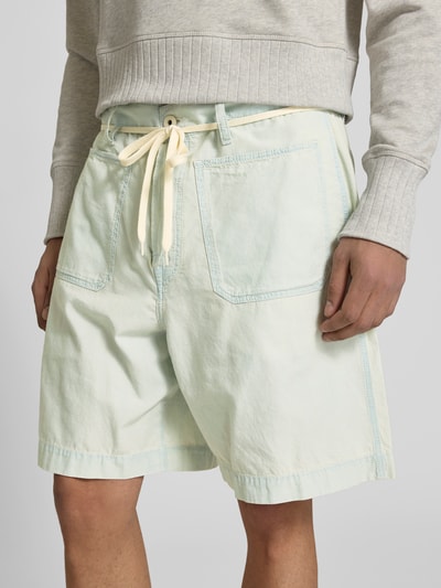 Männermodel trägt Shorts mit aufgesetzten Taschen von Kenzo aus reiner Baumwolle, Relaxed-Fit, pastellgrün, Nahaufnahme Oberkörper.