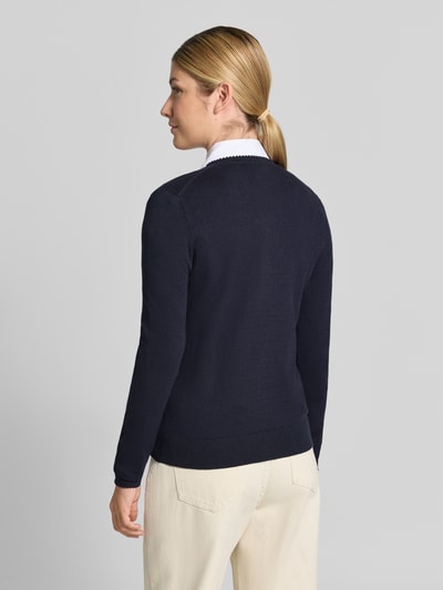 Vrouwenmodel draagt Regular Fit gebreid jack uit Viscosemix met geschulpte zoom van Christian Berg Woman, lange mouw, ruglengte maat S 56 cm, mouwlengte 61 cm, geribde boorden, knoopsluiting, effen donkerblauw, Ganzkörperansicht Rückansicht.