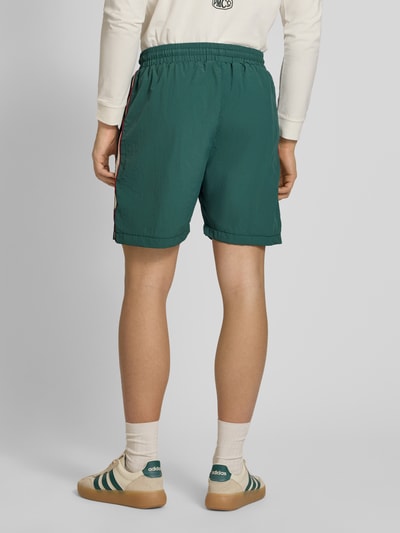 Männermodel trägt Shorts mit Label-Stitching Modell 'Slipstream' von PROHIBITED in Grün, elastischer Bund, Ganzkörperansicht Rückansicht.