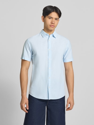 Męskki model nosi Regular Fit Freizeithemd aus Baumwoll-Leinen-Mix von Jack & Jones, mieszanka bawełny i lnu, krój regular fit, model BREEZE, kołnierzyk typu kent, listwa guzikowa, długość tyłu w rozmiarze M: 76 cm, szerokość w rozmiarze M: 50 cm, długość rękawów w rozmiarze M: 26 cm, jasnoniebieska koszula casualowa, gładka faktura, widok całej sylwetki z przodu.