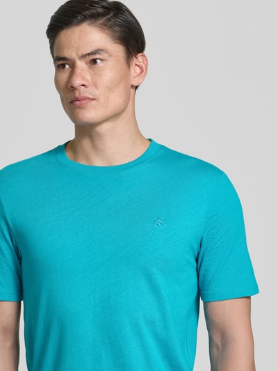 Männermodel trägt Regular Fit T-Shirt mit Logo-Stitching von Scotch & Soda in Türkis, reine Baumwolle, Rundhalsausschnitt, Nahaufnahme Oberkörper.