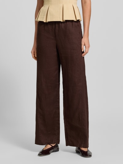 Frauenmodel trägt Leinenhose mit elastischem Bund Modell 'Mileni resort' von OPUS, dunkelbraun, Wide-Leg-Fit, Eingrifftaschen, reine Leinenstruktur, Ganzkörperansicht von vorne.