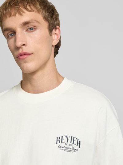 Männermodel trägt T-Shirt mit Label-Detail von REVIEW aus reiner Baumwolle, lockerer Schnitt, Rundhalsausschnitt, Nahaufnahme Oberkörper.