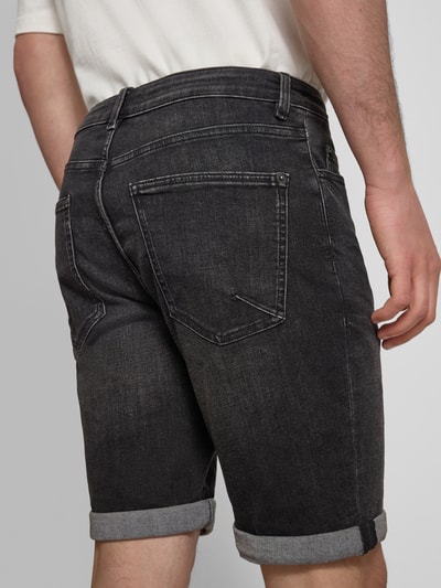 Männermodel trägt Slim Fit Jeansshorts mit Umschlag von REVIEW, dunkler Baumwoll-Mix mit Stretch, sichtbare Gesäßtaschen, Ganzkörperansicht Rückansicht.