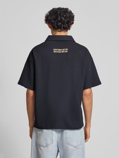 Männermodel trägt schwarzes Regular Fit Poloshirt aus Waffel-Piqué Modell 'Peace' von ANOTHER COTTON LAB, Rückansicht Ganzkörperansicht.
