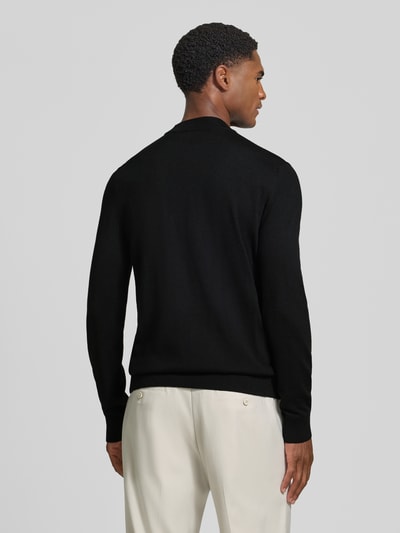 Männermodel trägt schwarzen Regular Fit Pullover aus reiner Schurwolle Modell 'Davide' von JOOP! COLLECTION, Ganzkörperansicht Rückansicht.