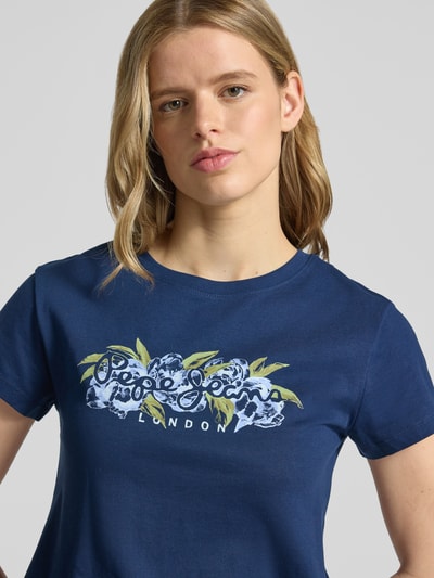 Frauenmodel trägt Regular Fit T-Shirt aus reiner Baumwolle Modell 'MAHINA' von Pepe Jeans, unifarben, Motiv-Print, Nahaufnahme Oberkörper.