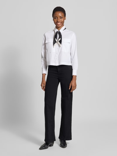Kobiece modelka nosi Flared Fit Jeans aus Baumwoll-Mix od Liu Jo White, czarny kolor, detal z logo, 5 kieszeni, zapięcie na guzik i zamek błyskawiczny, szerokość w rozmiarze 27: 36 cm, długość wewnętrzna nogawki w rozmiarze 27: 83 cm, mieszanka bawełny, zdjęcie całej sylwetki z przodu.