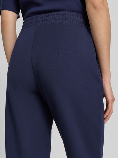 Frauenmodel trägt Straight Fit Sweatpants in verkürzter Passform von Christian Berg Woman aus Elastischer-Material-Mix mit Modal-Anteil, Dunkelblau, feine Textur, Bundfalten, Elastischer Bund, Detailaufnahme Rückansicht.
