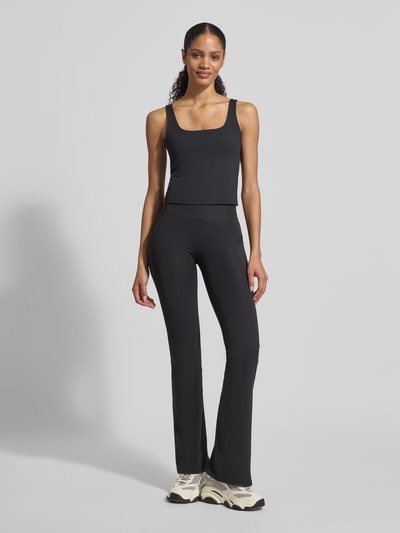 Frauenmodel trägt Slim Fit Top mit integriertem BH Modell 'Pureluxe' von Fabletics in Schwarz, tiefer Rundhalsausschnitt, Rückenlänge bei Größe S 30 cm, Ganzkörperansicht von vorne.