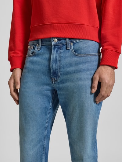 Mężczyznamodel nosi Slim Fit Jeans mit Logo-Patch Modell 'Clearwater' von Calvin Klein Jeans z mieszanki bawełny, 5 kieszeni, naszywka z logo, zapięcie na guzik i zamek błyskawiczny, szerokość w rozmiarze 32/32: 42 cm, długość wewnętrzna nogawki: 80 cm, niebieski kolor, wyraźne przeszycia, gładka faktura, krój slim fit, ujęcie: z bliska na biodra i uda.