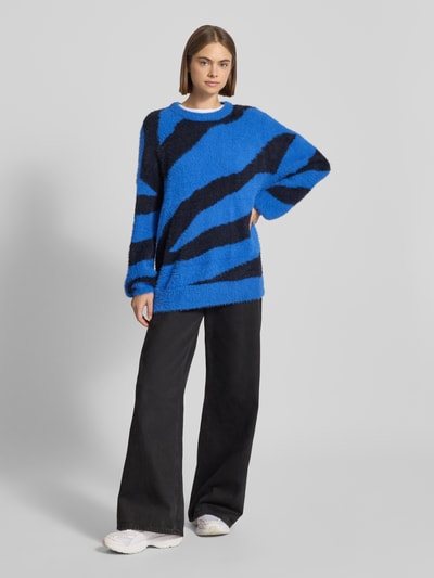 Frauenmodel trägt Strickpullover mit Rundhalsausschnitt Modell 'HEIDI' von Noisy May, relaxed Fit, blau-schwarzer Allover-Look, Ganzkörperansicht von vorne.