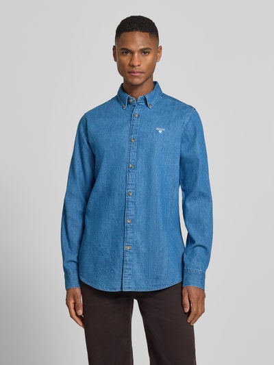 Männermodel trägt Slim Fit Jeanshemd aus reiner Baumwolle von Barbour in Denim-Optik, Label-Stitching-Applikation, Ganzkörperansicht von vorne.