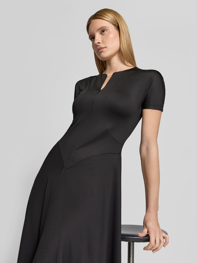 Frauenmodel trägt Midikleid mit verlängerter Rückseite von Victoria Beckham, schwarz, elastischer Material-Mix, Regular Fit, Nahaufnahme Oberkörper.