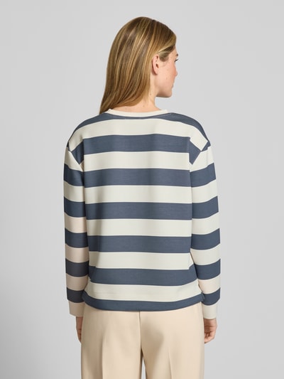Modelka nosi bluzę 'Sweatshirt mit Rundhalsausschnitt' od Christian Berg Woman, mieszanka materiałów z domieszką modalu, krój relaxed fit, okrągły dekolt, wzór na całej powierzchni, szerokie paski w kolorze kremowym i granatowym, widoczna faktura miękkiego materiału, widok całej sylwetki od tyłu.