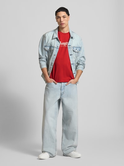 Männermodel trägt Regular Fit T-Shirt mit Logo-Print von JACK & JONES in Rot, Baumwolle, Rundhalsausschnitt, Ganzkörperansicht von vorne.