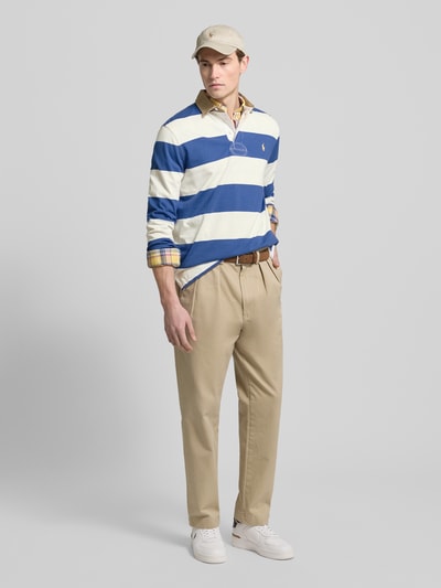 Mężczyzna nosi bluzę Sweatshirt mit Label-Stitching od Polo Ralph Lauren z bawełny, krój regular fit, kołnierzyk polo, listwa guzikowa, prążkowane zakończenia rękawów, długość tyłu 66 cm, długość rękawa 20 cm, widok całej sylwetki z przodu.