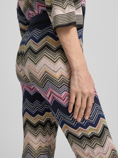 Frauenmodel trägt Flared Hose aus Viskose-Mix im Allover-Look von Oui, gemusterter Stoff, elastischer Bund, Nahaufnahme Hüfte und Oberschenkel.
