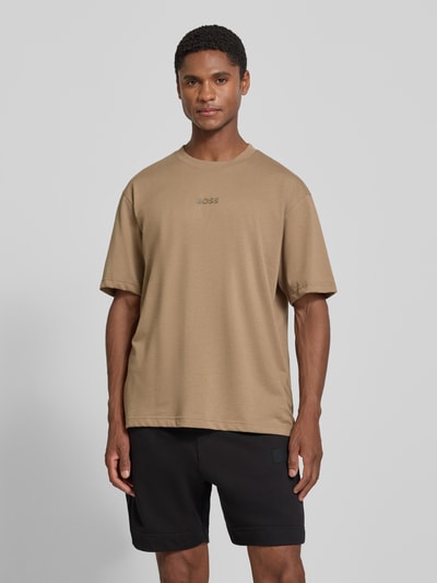 Männermodel trägt Relaxed Fit T-Shirt aus reiner Baumwolle Modell 'TEE 10' von BOSS für BOSS Green in Beige, glatte Struktur, Ganzkörperansicht von vorne.