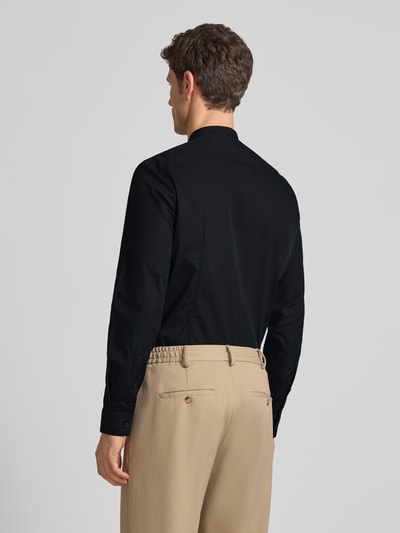 Męski model nosi Slim Fit Businesshemd aus reiner Baumwolle Modell 'KALEB' von HUGO, efekt: jednolity kolor, stójka, długi rękaw, zaokrąglony dół, Kombimanschetten, czarna bawełna, aplikacja z wyhaftowanym logo, całkowity widok z tyłu.