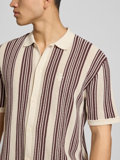 Männermodel trägt Regular Fit Strickhemd mit Logo-Stickerei auf der Brust von REVIEW aus reiner Baumwolle, Streifenmuster, Nahaufnahme Oberkörper.